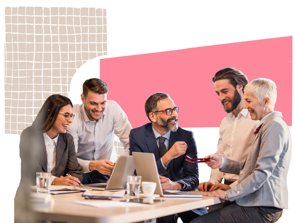 Team im Meeting lacht und arbeitet gemeinsam am Laptop.